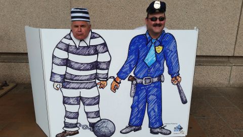 1991 Ford LTD Crown Victoria - Photo of a novelty face-cutout photo board showing cartoon prisoner and police officer figures.