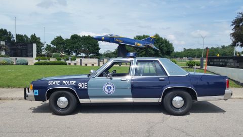 1991 Ford LTD Crown Victoria - Photo of a Massachusetts State Police Ford Crown Victoria cruiser, unit 90E, in profile near a display jet.