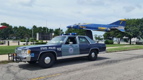 1991 Ford LTD Crown Victoria - Photo of a Massachusetts State Police Ford Crown Victoria cruiser, unit 90E, near a U.S. Navy display jet.