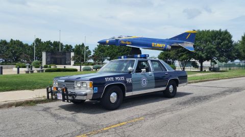 1991 Ford LTD Crown Victoria - Photo of a Massachusetts State Police Ford Crown Victoria cruiser, unit 90E, near a U.S. Navy display jet.