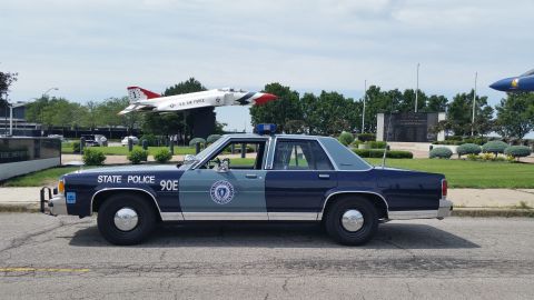 1991 Ford LTD Crown Victoria - Photo of a Massachusetts State Police Ford Crown Victoria cruiser, unit 90E, in profile near display aircraft.