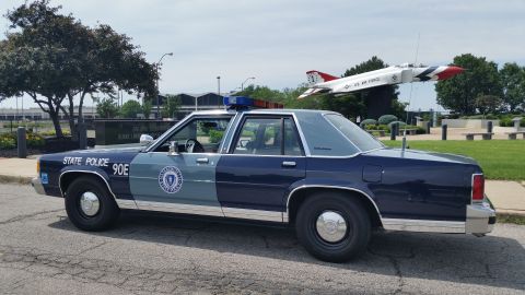 1991 Ford LTD Crown Victoria - Photo of a Massachusetts State Police Ford Crown Victoria cruiser, unit 90E, in profile near a display jet.