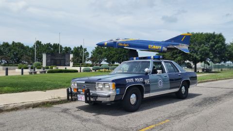 1991 Ford LTD Crown Victoria - Photo of a Massachusetts State Police Ford Crown Victoria cruiser, unit 90E, near a U.S. Navy display jet.