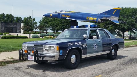 1991 Ford LTD Crown Victoria - Photo of a Massachusetts State Police Ford Crown Victoria cruiser, unit 90E, near a U.S. Navy Blue Angels display jet.