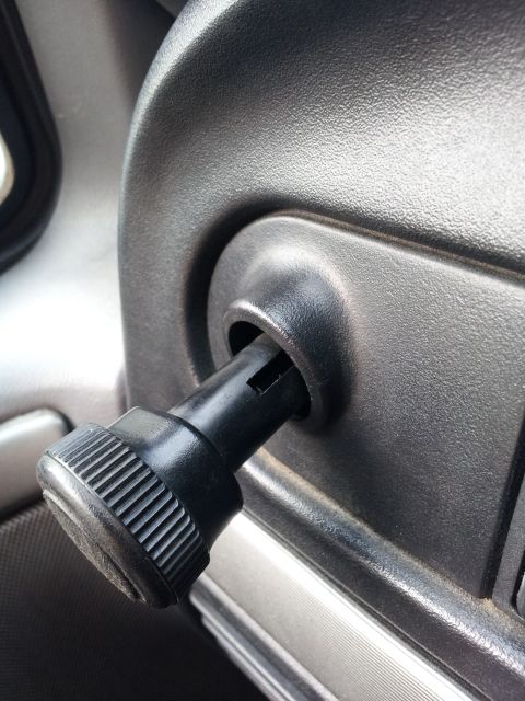 1995 Ford Bronco - A close-up view of a black rotary knob with ribbed texture, likely a control knob for a vehicle's interior, is inserted into a textured bla…