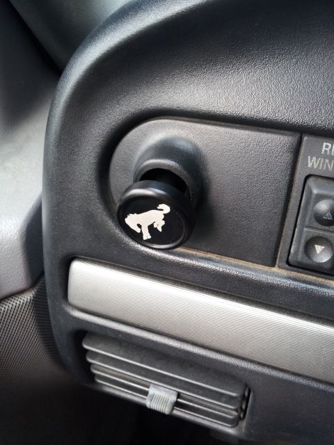 1995 Ford Bronco - A close-up interior shot shows a black circular knob with a white silhouette of a horse on it, inserted into the dashboard of a vehicle. To…