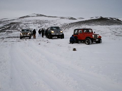 1996 Ford Bronco - Several vehicles and people are stopped in a snowy, hilly landscape.