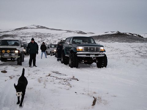 1996 Ford Bronco - A convoy of SUVs, including a lifted 1996 Ford Bronco, navigates a snowy landscape.