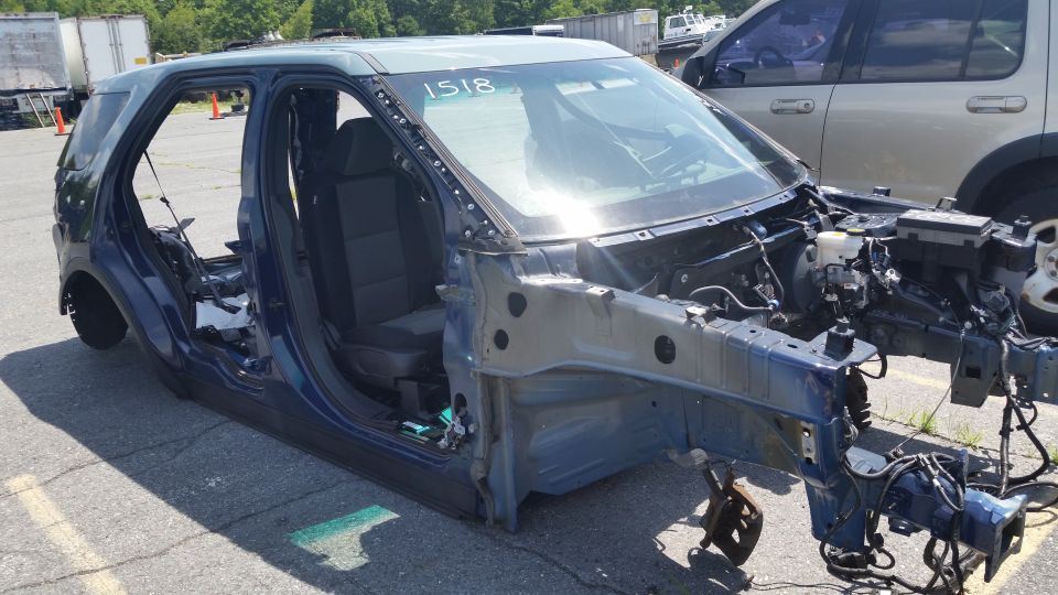Photo of a stripped SUV body shell with front structure and seats exposed in a yard