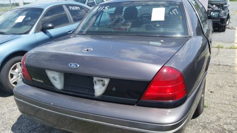 2001 Ford Crown Victoria - Photograph of the rear of a gray Ford sedan at a salvage lot, not a technical document.