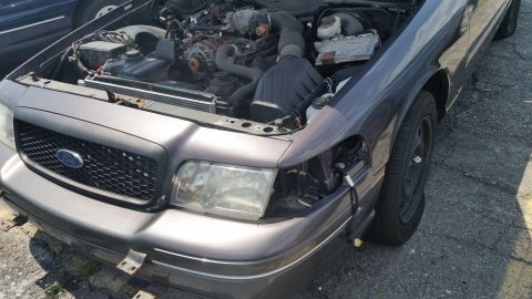 2001 Ford Crown Victoria - Photograph of a gray Ford sedan engine bay being dismantled, not a technical document.