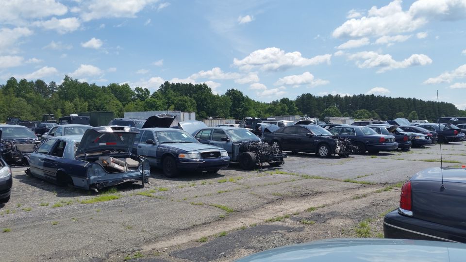Salvage lot with rows of damaged Crown Victoria police-style sedans