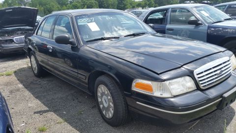 2001 Ford Crown Victoria - Photo of a black Ford Crown Victoria sedan with windshield chalk markings at a salvage yard.