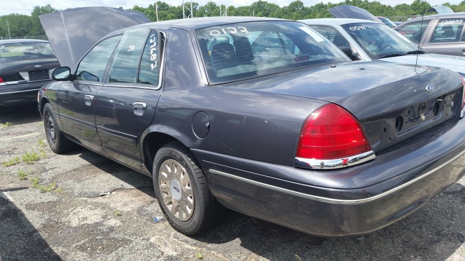 Gray Crown Victoria with open hood and chalk markings in a salvage yard