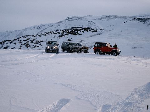 1996 Ford Bronco - Multiple SUVs are parked on a snow-covered hill under a cloudy sky.