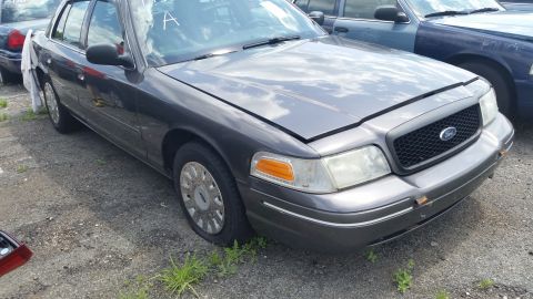 2001 Ford Crown Victoria - Dark gray 2001 Ford Crown Victoria with hood ajar, parked outdoors.