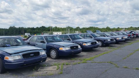 2001 Ford Crown Victoria - Multiple Ford Crown Victorias are lined up in a vehicle lot under a cloudy sky.