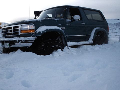 1996 Ford Bronco - A 1996 Ford Bronco is stuck in a snowdrift, with its front tire almost completely submerged.