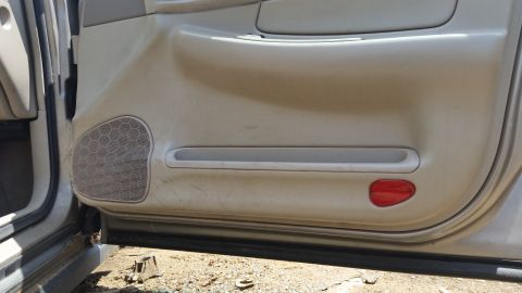 2001 Ford Crown Victoria - Interior door panel of a car, showing speaker grille and reflector.