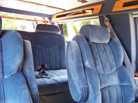 2000 Ford E150 - The plush blue interior of a van, captain's chairs and wood trim accents.