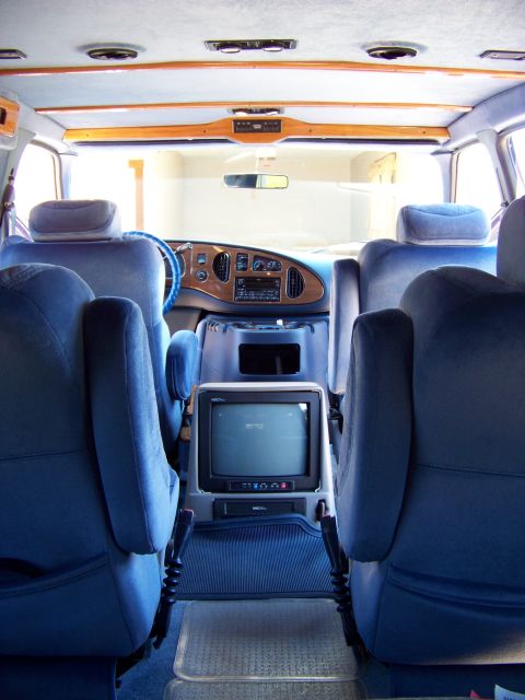 2000 Ford E150 - The interior of this van features plush blue seating, wood accents, and a built-in television, suggesting a conversion van from the 1990s.