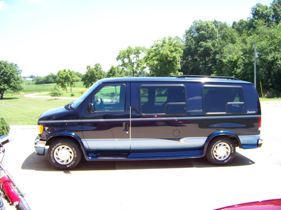 Dark blue Ford E-Series van with silver and light blue stripe, parked outdoors on a paved surface