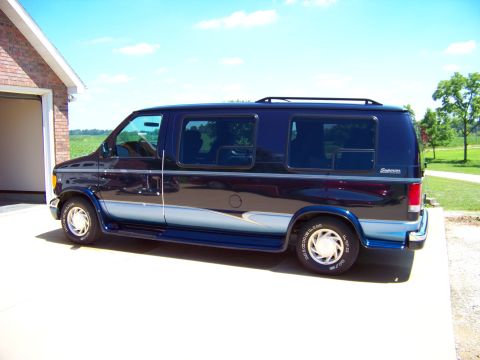 2000 Ford E150 - This 2000 Ford E150 van is shown from the side, a dark blue exterior with contrasting light blue accents along the lower body.