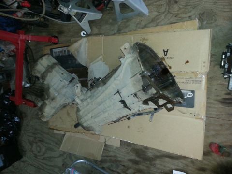 1995 Ford Bronco - Several transmission and transfer case parts are laid out on cardboard boxes in a garage setting.