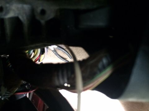 1994 Ford Bronco - A close-up view of a vehicle's wiring harness, with a pair of pliers resting nearby.