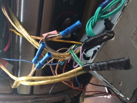 1994 Ford Bronco - Close-up of aftermarket car stereo wiring connections, including speaker wires and power cables.