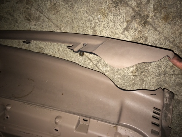 Two beige plastic interior trim pieces on a concrete surface.