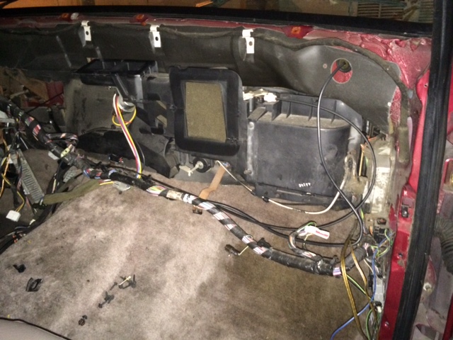 Interior of a vehicle with dashboard removed, showing HVAC and wiring harness.