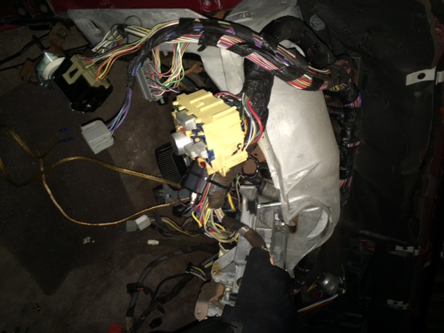 Vehicle dashboard wiring harness with yellow fuse box and connectors.