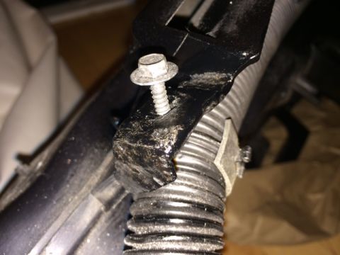 1994 Ford Bronco - A close-up shot shows a hex bolt securing a black bracket to a ribbed black hose. A small metal clamp is also visible, attached to the hose.