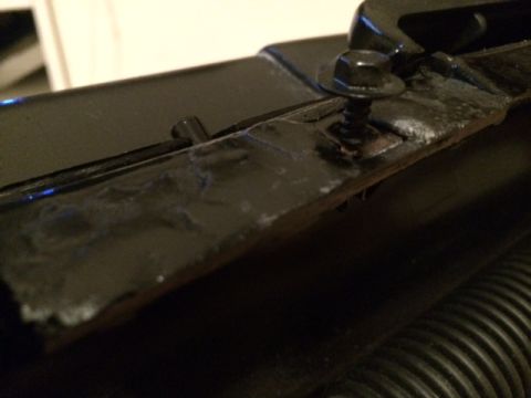 1994 Ford Bronco - A close-up, angled shot shows a black metal bracket with a hex bolt and washer securing it. The bracket appears to be part of a vehicle's u…