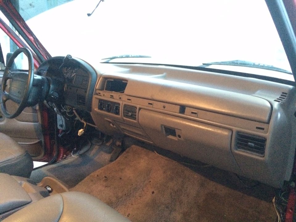 Interior view of a vehicle dashboard with steering wheel and beige trim.