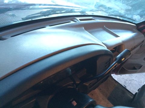 1994 Ford Bronco - The interior of a vehicle shows the dashboard and steering column. A dark-colored gear shifter extends from the center console.