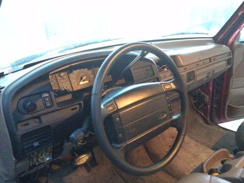 1994 Ford Bronco - The interior of a Ford Bronco shows the dashboard, steering wheel, and driver's side door. The dashboard features gauges, vents, and contro…