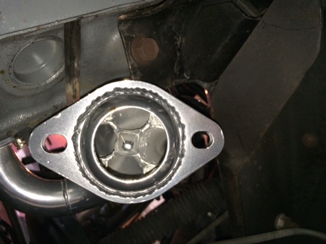Custom exhaust manifold flange with internal vanes on a vehicle engine.