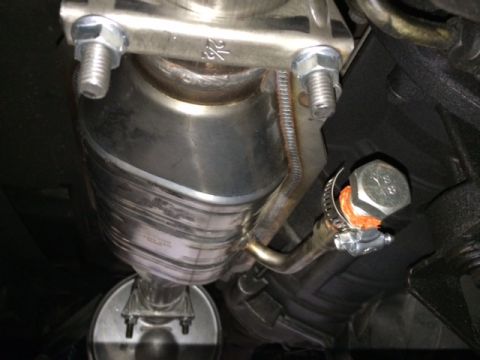 1994 Ford Bronco - A close-up, low-angle view of the underside of a vehicle's exhaust system, featuring a catalytic converter and a bolted clamp with an orang…