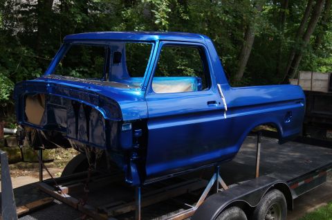 1979 Ford Bronco - A bare blue Ford Bronco body is mounted on a trailer for painting. The vehicle is missing its engine, doors, and hood, revealing the interi…