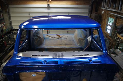 1979 Ford Bronco - The front end of a classic pickup truck cab is shown, freshly painted in a metallic blue finish. The interior is partially covered with pla…