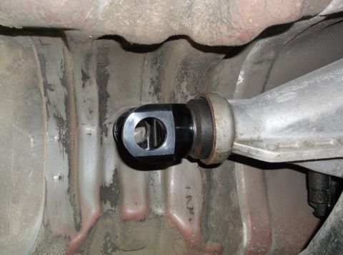 1999 Mercury Grand Marquis - A close-up view shows a black aftermarket part installed on the rear suspension of a vehicle. The part appears to be a bushing or mount con…