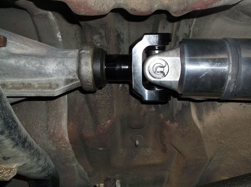 Close-up of a vehicle's driveshaft and differential connection with a custom aluminum driveshaft.