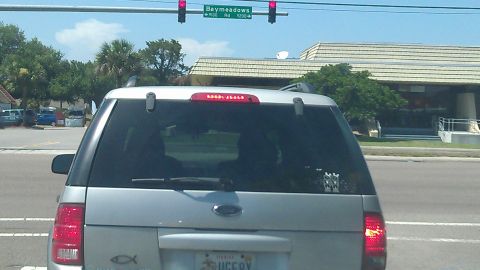 1994 Ford Bronco - The rear view of a silver Ford SUV is shown, stopped at a traffic light. A Florida license plate is visible, reading "SUGERY".