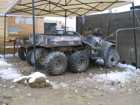 1981 Ford Bronco - A Polaris ATV and trailer are parked outdoors in a muddy, snowy environment.