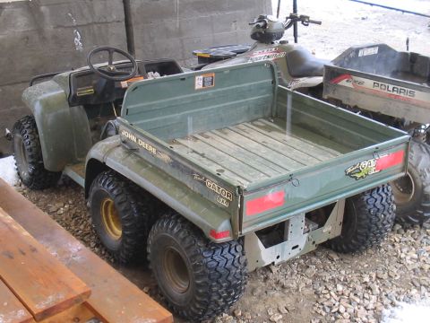 1981 Ford Bronco - A John Deere Trail Gator utility vehicle is shown from the rear, parked indoors with other recreational vehicles.
