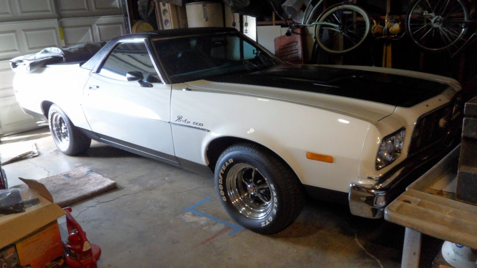 1972 Ford Ranchero with black hood and vinyl top, parked in a garage.