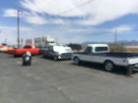 1968 Ford Mustang - Multiple vehicles are parked in an outdoor lot under a cloudy sky.