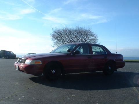 1999 Ford Crown Victoria - A red 1998 Ford Crown Victoria sedan is parked outdoors on a sunny day with a tree and another vehicle in the background.